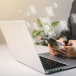 A businessman works on his laptop at home with a virtual display showing a symbol to signify cyber security privacy and online data protection